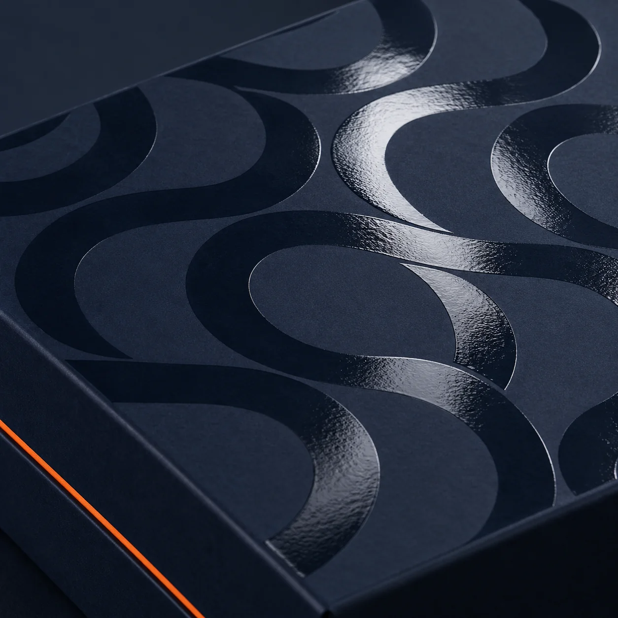 Glossy spot UV curved pattern against a matte navy box lid